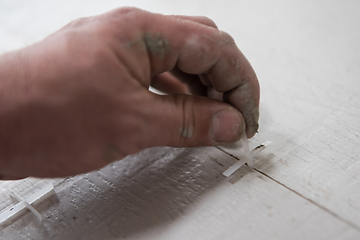 Image showing worker installing the ceramic wood effect tiles on the floor