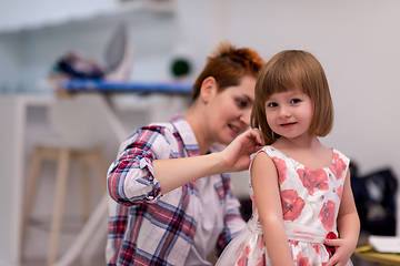 Image showing mother helping daughter while putting on a dress