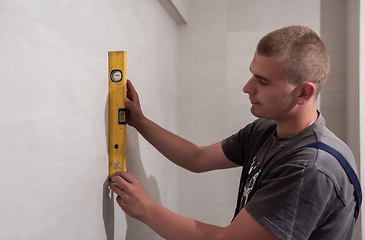 Image showing professional plumber using bubble level in a bathroom