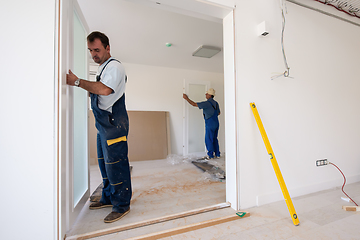 Image showing carpenters installing glass door with a wooden frame