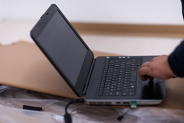 Image showing man using laptop while lying on cardboard box