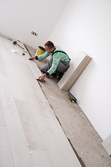 Image showing worker installing the ceramic wood effect tiles on the floor