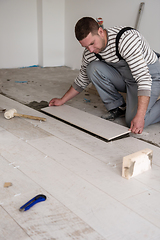 Image showing worker installing the ceramic wood effect tiles on the floor