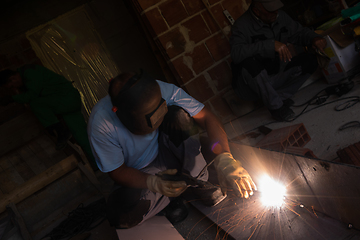 Image showing welder with protective mask welding steel