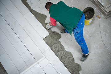 Image showing worker installing the ceramic wood effect tiles on the floor