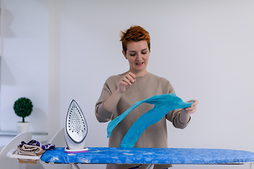 Image showing Red haired woman ironing clothes at home
