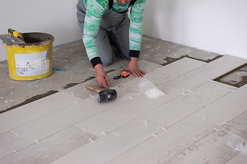 Image showing worker installing the ceramic wood effect tiles on the floor