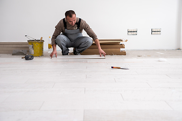 Image showing worker installing the ceramic wood effect tiles on the floor