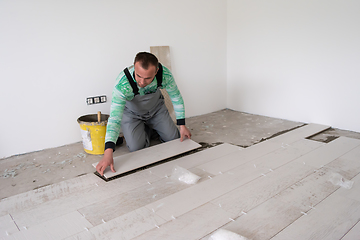 Image showing worker installing the ceramic wood effect tiles on the floor