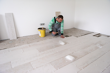 Image showing worker installing the ceramic wood effect tiles on the floor