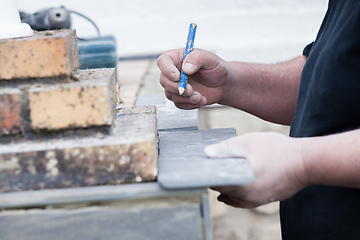 Image showing the tiler measures and puts marks to cut and lay a tile