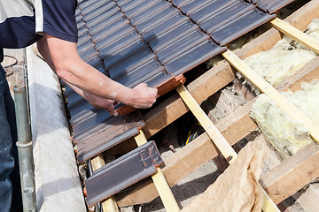 Image showing a roofer laying tile on the roof