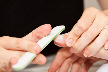 Image showing The beautician polish the client\'s nails before putting nail pol