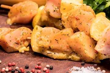 Image showing raw chicken skewers marinated with lemon on a wooden board