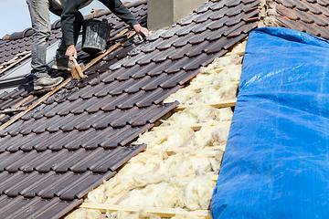 Image showing a roofer laying tile on the roof