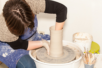 Image showing Female Potter creating a earthen jar on a Potter\'s wheel
