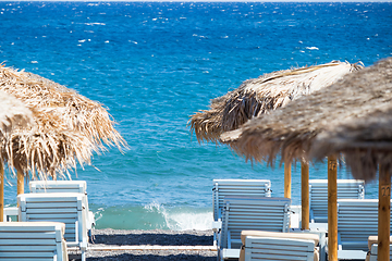 Image showing beach with umbrellas and deck chairs by the sea in Santorini