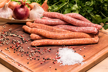 Image showing raw sausages with chilli and herbs on a wooden board with spices