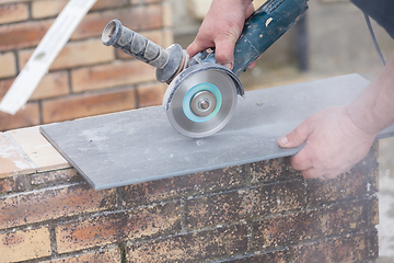 Image showing tiler cutting a tile with a grinder