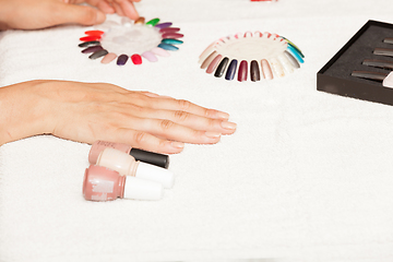 Image showing Hands of a woman who chooses the color of her nail polish