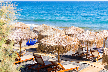 Image showing beach with umbrellas and deck chairs by the sea in Santorini