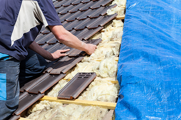 Image showing a roofer laying tile on the roof