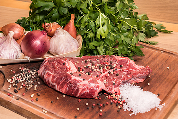 Image showing steak of beef on a wooden board with spices pepper parsley salt 