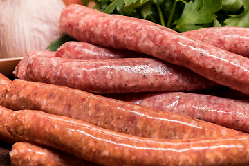 Image showing raw sausages with chilli and herbs on a wooden board with spices