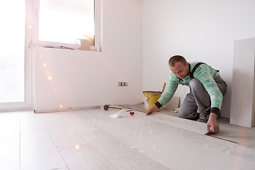 Image showing worker installing the ceramic wood effect tiles on the floor