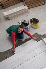 Image showing worker installing the ceramic wood effect tiles on the floor