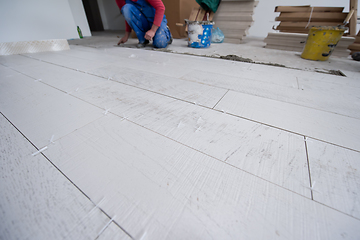 Image showing worker installing the ceramic wood effect tiles on the floor