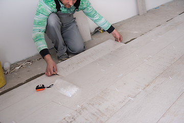 Image showing worker installing the ceramic wood effect tiles on the floor