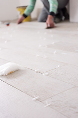 Image showing worker installing the ceramic wood effect tiles on the floor