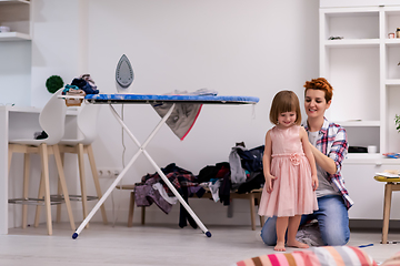 Image showing mother helping daughter while putting on a dress