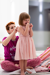 Image showing young mother helping daughter while putting on a dress