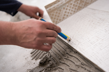 Image showing worker installing the ceramic wood effect tiles on the floor