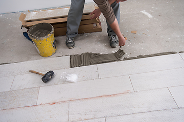 Image showing worker installing the ceramic wood effect tiles on the floor