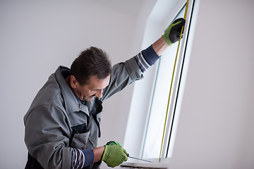 Image showing man installing window with measure tape