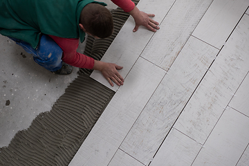 Image showing worker installing the ceramic wood effect tiles on the floor