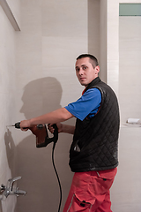 Image showing construction worker drilling holes in the bathroom