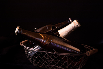 Image showing beer bottles on a black background chiaroscuro in an old metal m