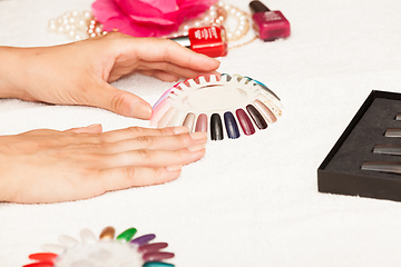 Image showing Hands of a woman who chooses the color of her nail polish