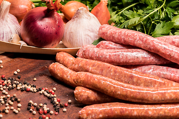 Image showing raw sausages with chilli and herbs on a wooden board with spices