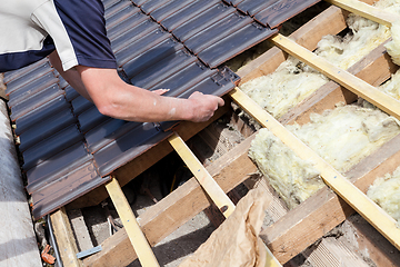 Image showing a roofer laying tile on the roof