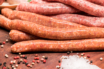 Image showing raw sausages with chilli and herbs on a wooden board with spices