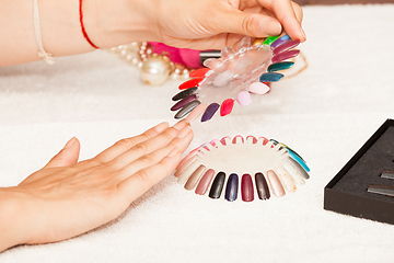 Image showing Hands of a woman who chooses the color of her nail polish