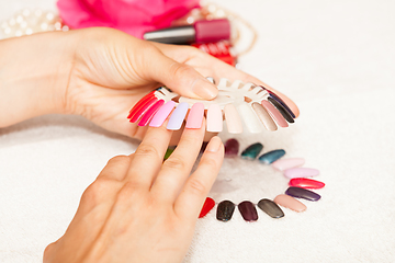 Image showing Hands of a woman who chooses the color of her nail polish