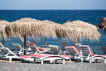 Image showing beach with umbrellas and deck chairs by the sea in Santorini