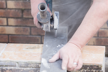 Image showing tiler cutting a tile with a grinder