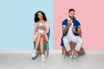 Image showing Young emotional man and woman on pink and blue background